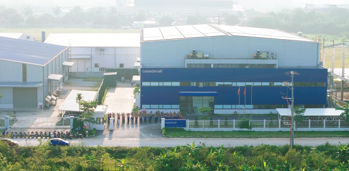 The Casadevall Vietnam factory at dawn, its blue block and production halls seen across the fields.